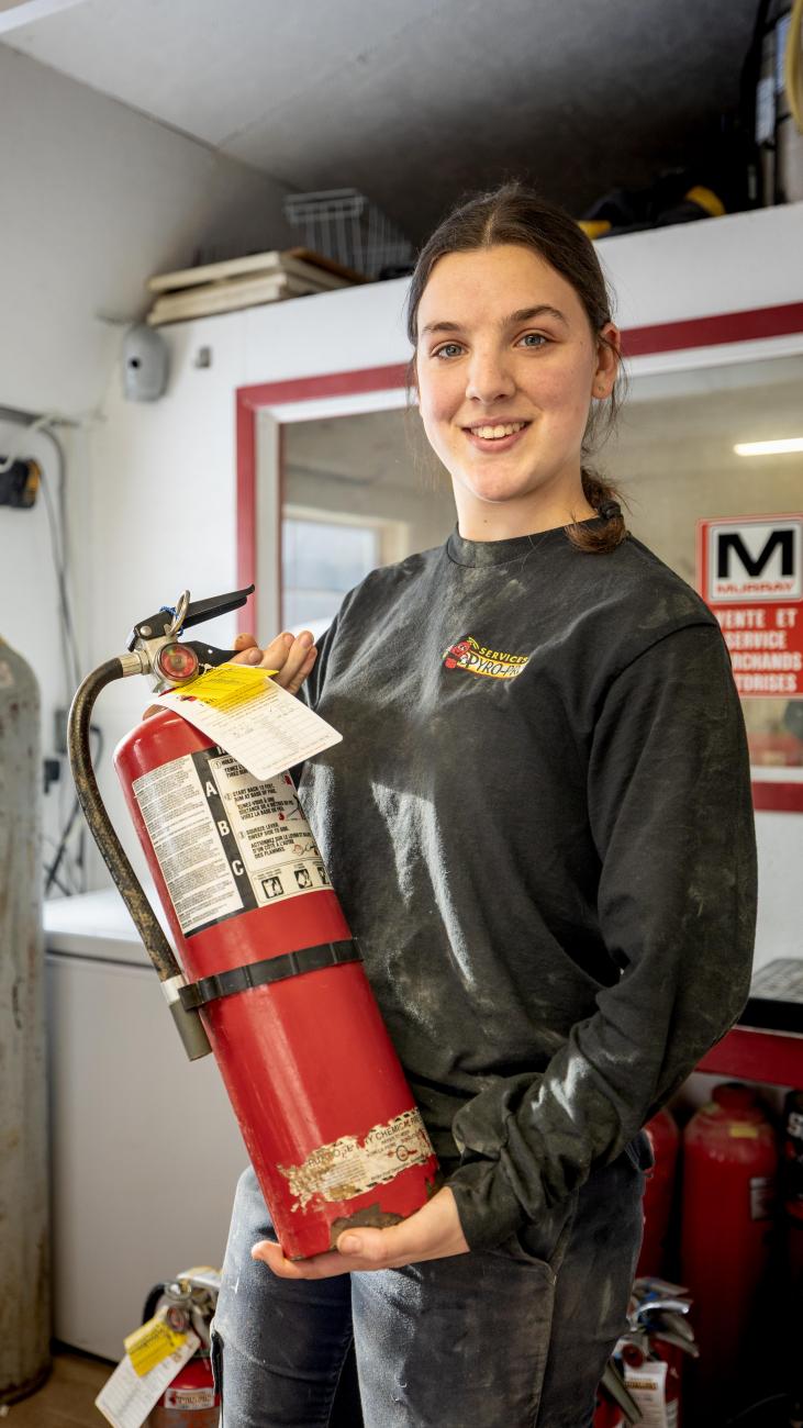 Dana, technicienne à l'atelier, tenant un extincteur en maintenance